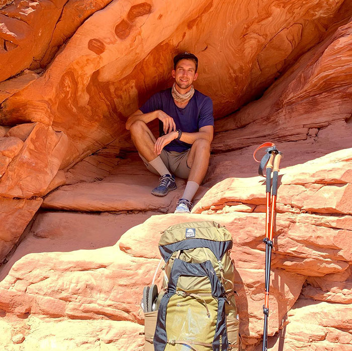 YouTube star sitting in red rock alcove with hiking gear. YouTube star sitting in red rock alcove with hiking gear.