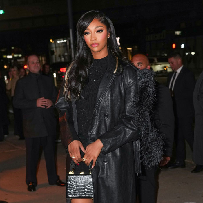Angel Reese in a stylish black outfit at a nighttime event, amidst a debate on her net worth.