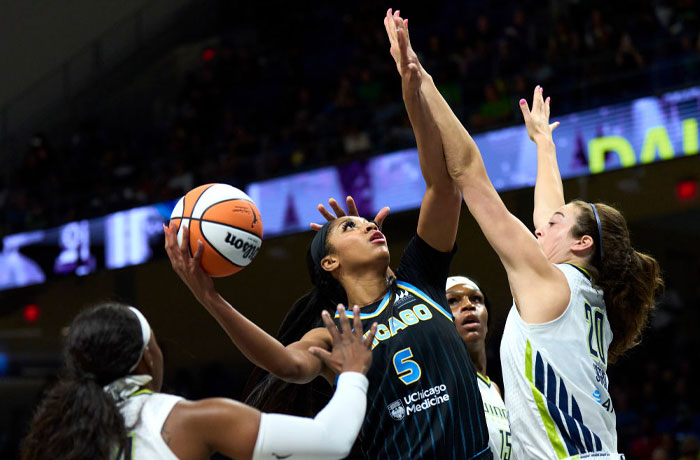 Basketball player Angel Reese in action, holding a ball and being defended, illustrating debate around net worth estimates.