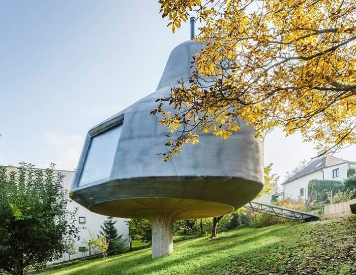 Casa futurista elevada sobre un pilar en un paisaje otoñal, ejemplo de arquitectos criticados.