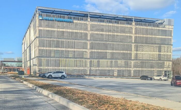 Edificio con diseño arquitectónico cuestionable en un estacionamiento vacío bajo un cielo azul.