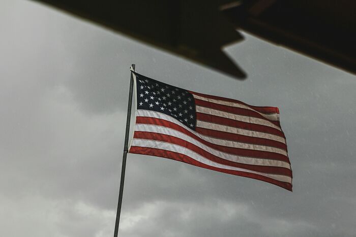 American flag waving against a cloudy sky, challenging common stereotypes.