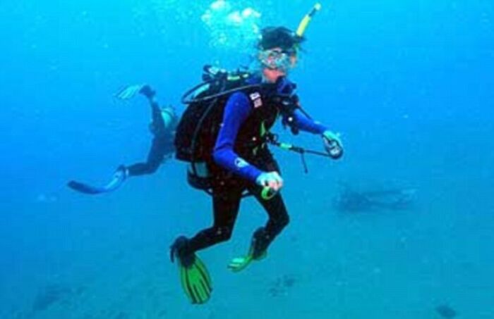 Divers exploring underwater, capturing creepy photo with mysterious dark history, amidst blue ocean surroundings.