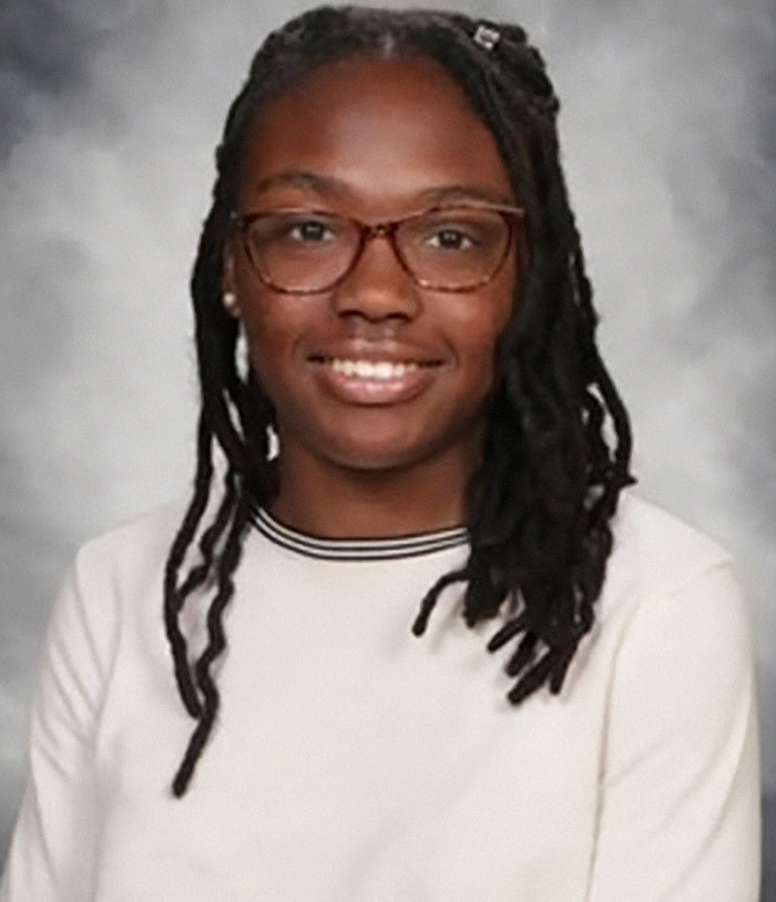 Girl found in another state after a year, wearing glasses and smiling, with a light background.