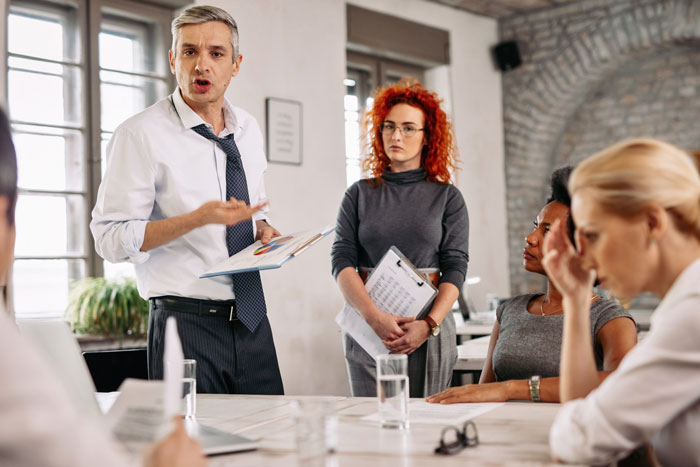 Office discussion with concerned individuals around a table, addressing breakroom issues.