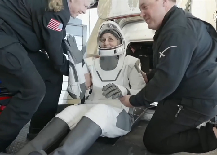 Astronaut in space suit assisted by crew after landing, highlighting health concerns noticed by doctors.