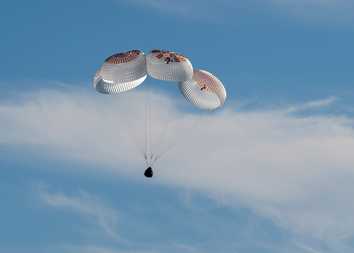 Parachutes deploy as spacecraft brings astronauts back to Earth safely.
