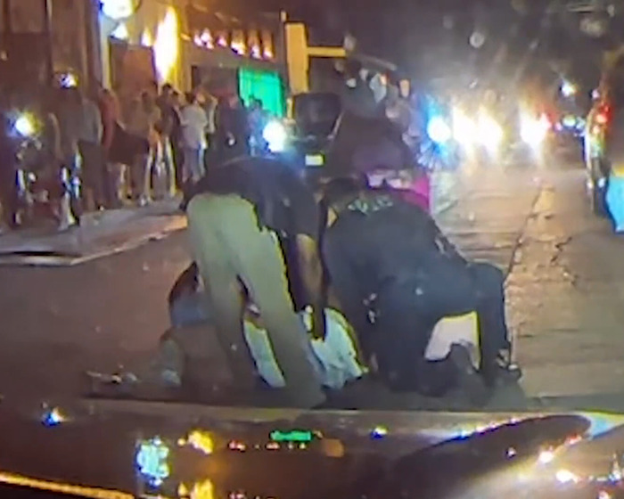 Police assist a woman during a nighttime incident on a busy street, related to a bride-to-be assault case.