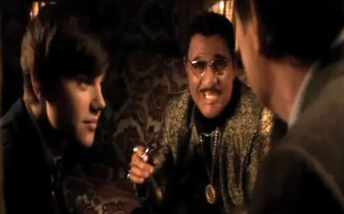 Three people in a dimly lit room, engaging in a heated discussion at an awards show.