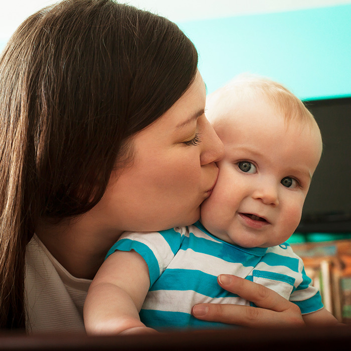 Woman kissing toddler, focusing on herpes virus risk to child's eye health. Woman kissing toddler, focusing on herpes virus risk to child's eye health.