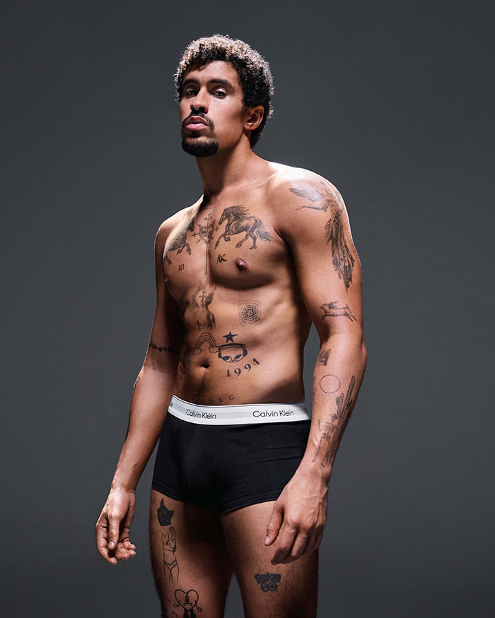 Model in Calvin Klein underwear with tattoos and noticeable bulge, featured in viral campaign linked to Bad Bunny's transformation.