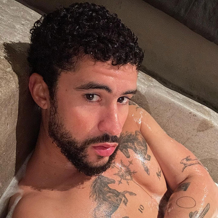 A person with tattoos poses shirtless, showcasing the viral Bad Bunny Calvin Klein campaign vibe.