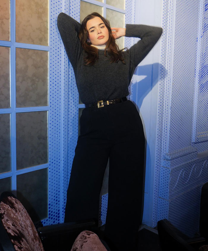 Barbie Ferreira posing confidently in a stylish outfit against a blue backdrop.