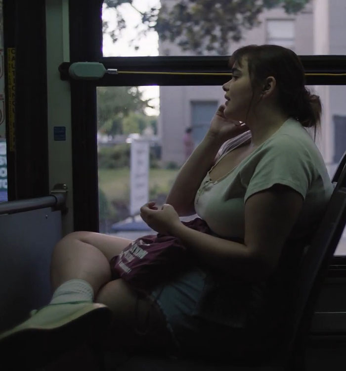 Barbie Ferreira on a bus, sitting by the window, deep in thought, in a scene from a movie before losing weight.