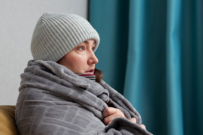 Person in knit hat and gray blanket, embodying basic knowledge and indoor comfort essentials.