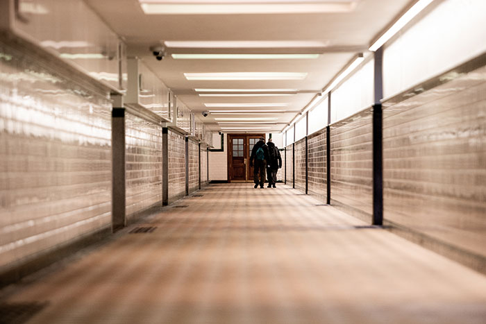 Two people walking in a hallway, illustrating everyday basic knowledge through simple movement.