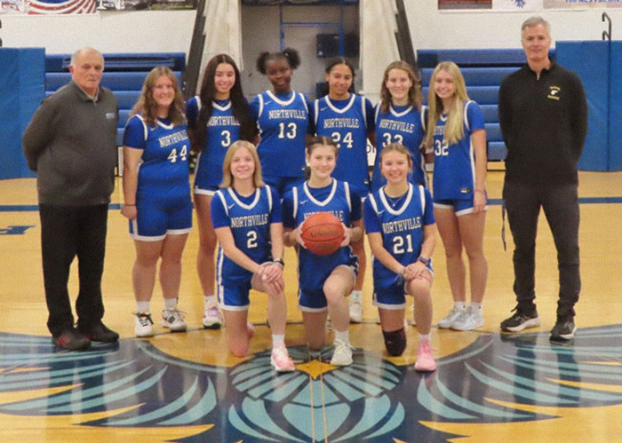 Youth basketball team with coaches, wearing blue jerseys, posing on the court. Main keywords: Lip Reader, Basketball Coach.