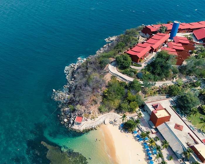 Aerial view of a Mexican tourist spot with red-roofed buildings by the ocean. Aerial view of a Mexican tourist spot with red-roofed buildings by the ocean.