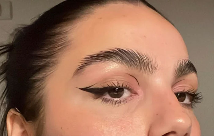 Close-up of dramatic eyebrow and eyeliner makeup, highlighting beauty trends.