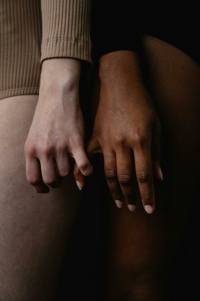 Two hands with different skin tones interlocked, symbolizing diverse beauty standards.