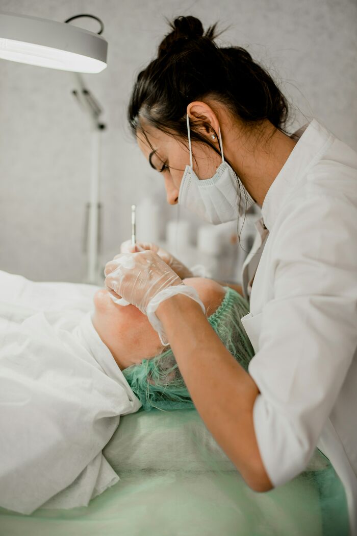 Beautician performing a procedure, showcasing beauty standards and trends, in a clinical setting.