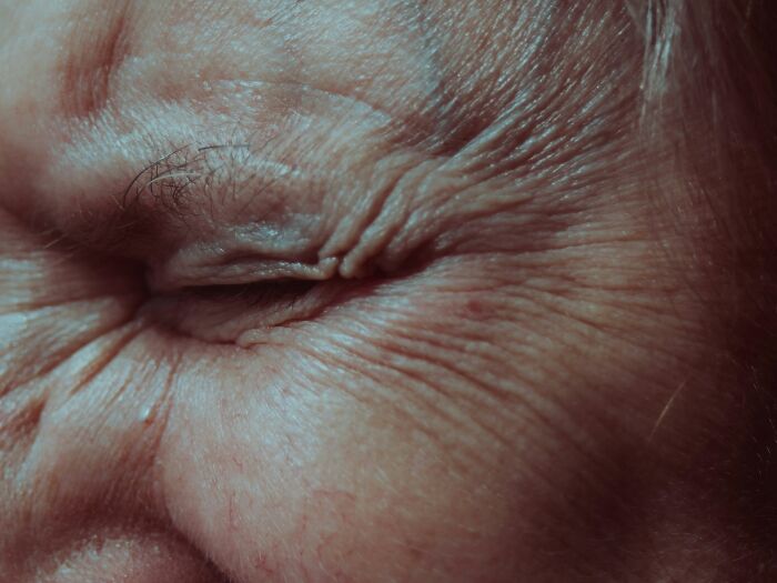 Close-up of an eye with natural wrinkles highlighting beauty standards.