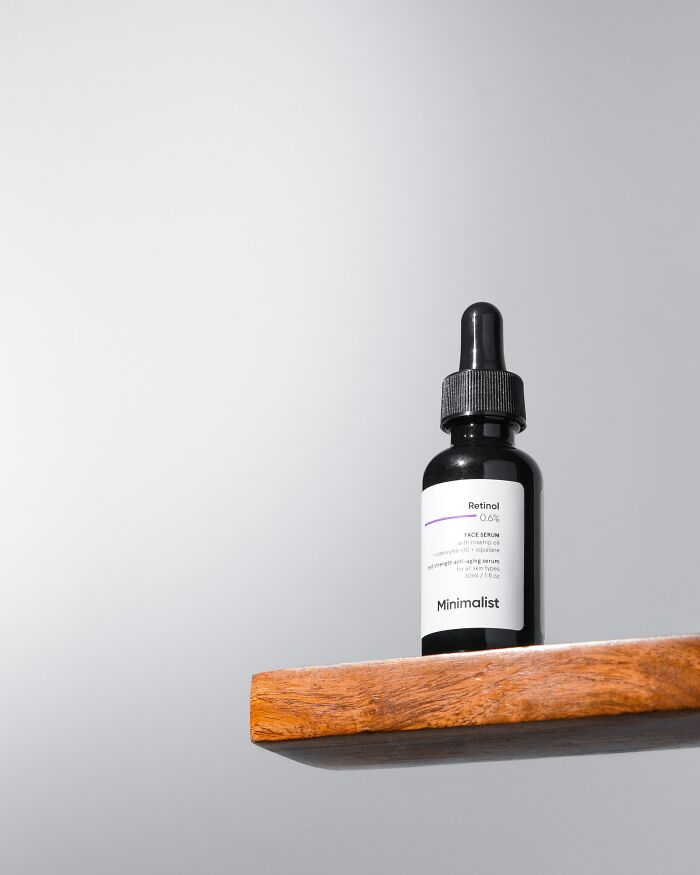 A bottle of Retinol serum on a wooden shelf, highlighting beauty standards.