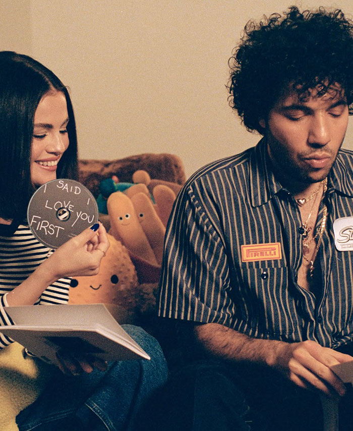 Two people sit together, one holding a sign. The person on the right, with transformed eyebrows, appears thoughtful. Two people sit together, one holding a sign. The person on the right, with transformed eyebrows, appears thoughtful.