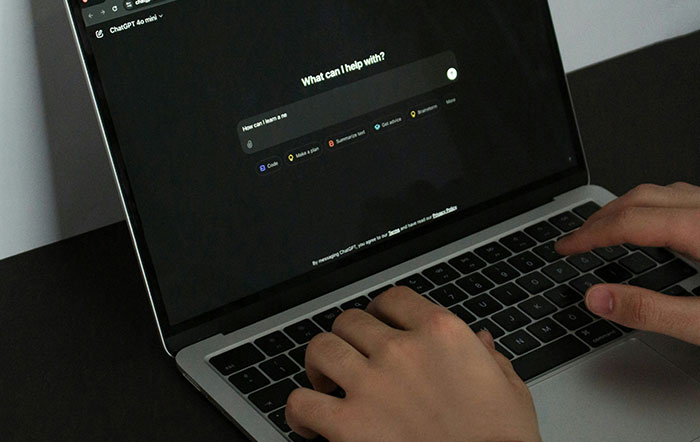 Hands typing on a laptop showing AI interface, highlighting environmental concerns.