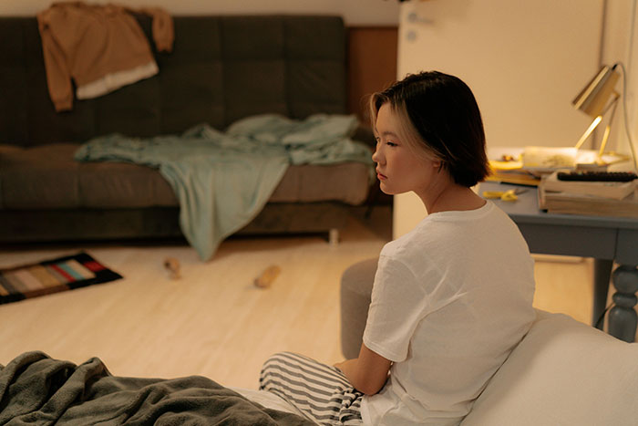 Person sitting in a cluttered room, reflecting on a best friend trash living situation, surrounded by scattered items.