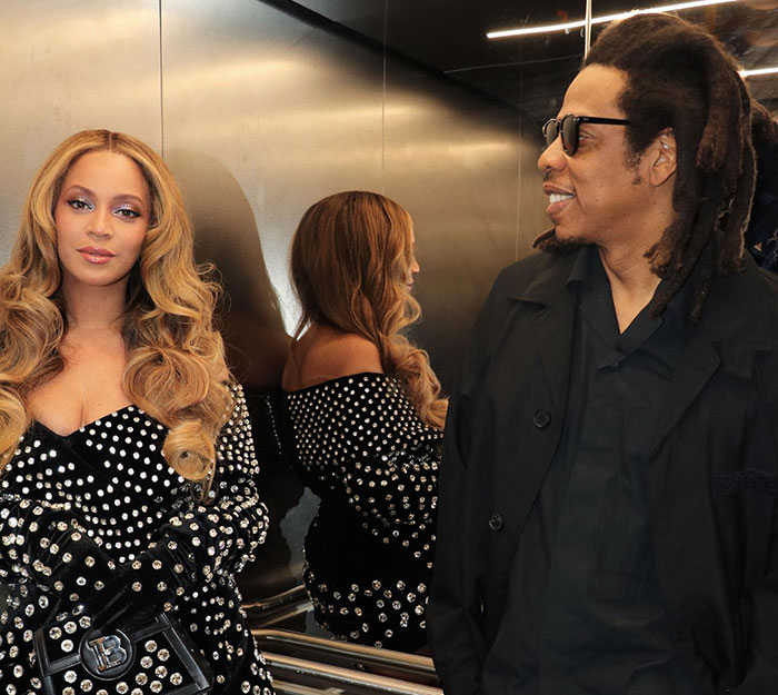 Beyonc&eacute; and Jay-Z in an elevator, Beyonc&eacute; wearing a studded outfit, Jay-Z smiling in a black jacket and sunglasses.