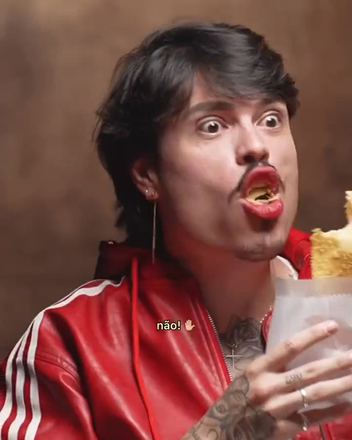 Individual in a red jacket appearing surprised while eating, connected to reactions involving Millie Bobby Brown and Brazilians.