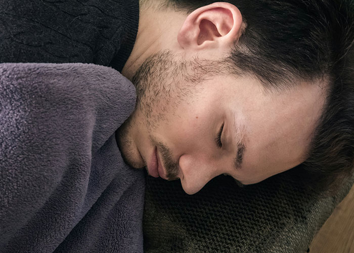 Man sleeping with a blanket, appearing normal, embodying a curious and relatable sleeping habit. Man sleeping with a blanket, appearing normal, embodying a curious and relatable sleeping habit.