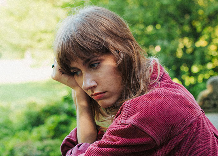 Woman looking contemplative in a garden, reflecting on boyfriend's unusual sleeping habit. Woman looking contemplative in a garden, reflecting on boyfriend's unusual sleeping habit.