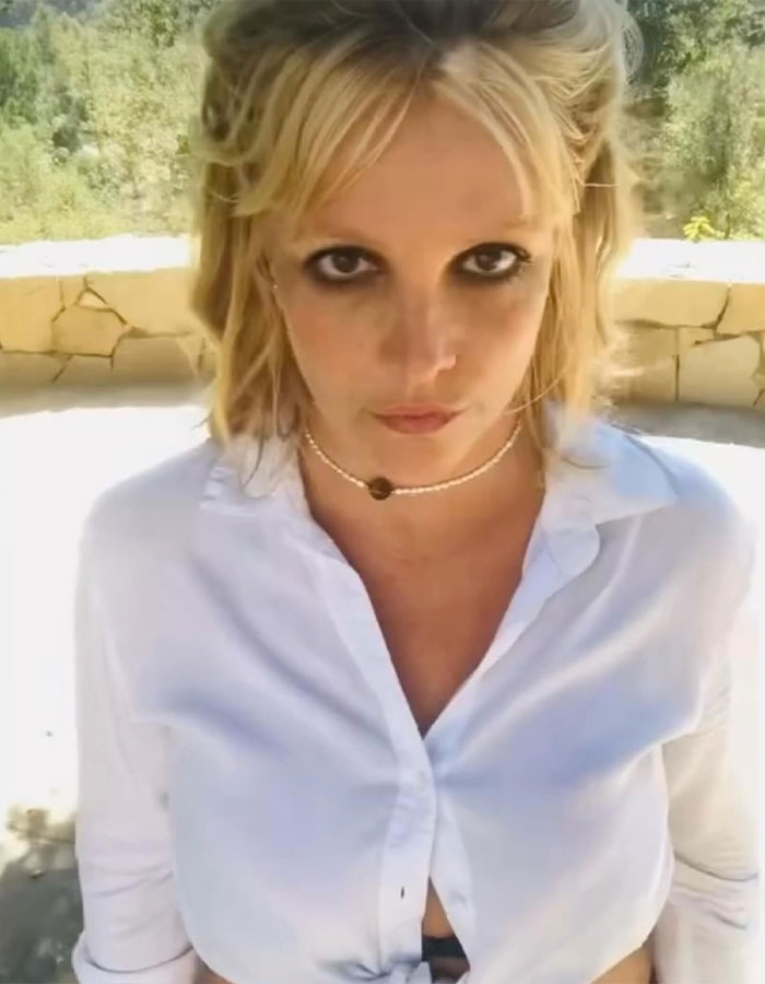 A woman outdoors wearing white, looking directly at the camera with light makeup and layered hair. A woman outdoors wearing white, looking directly at the camera with light makeup and layered hair.