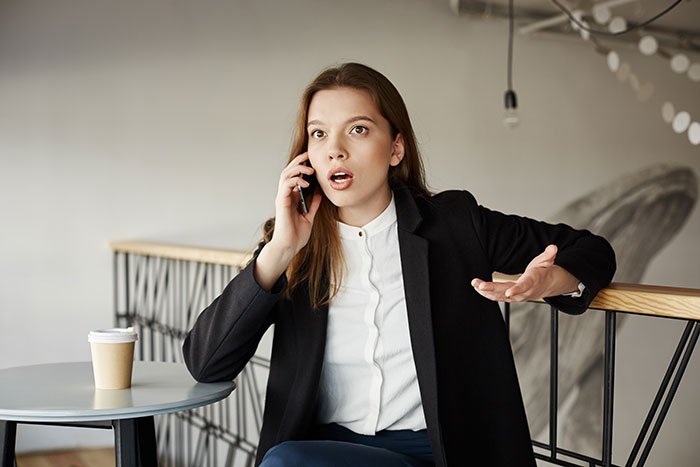 Bride looking baffled during a phone call, expressing surprise, related to a brother's unexpected wedding invitation choice.