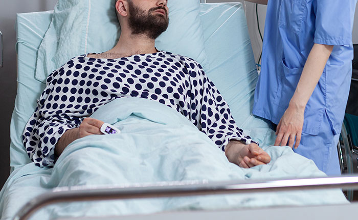 Man in hospital bed with nurse, illustrating concept of choosing a female friend over the long-term girlfriend for wedding invitation.