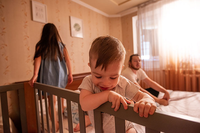 Man with children in a bedroom, highlighting family dynamics and parenting challenges.