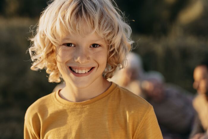 Smiling child outdoors in a yellow shirt, highlighting ridiculous bullying experiences.