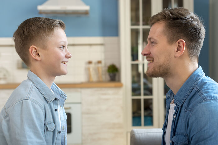 A child and adult smiling at each other in a kitchen, highlighting disbelief over bullying.