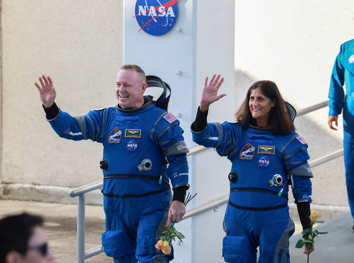 Astronauts in blue suits waving, highlighting effects of space travel on the body.