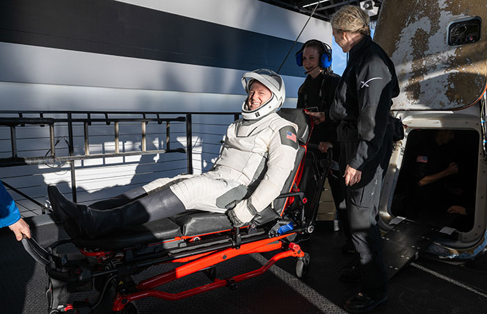 Doctor assisting stranded astronaut on a stretcher after landing, sparking concern.