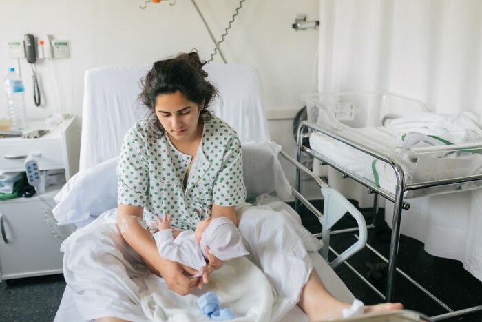 Woman in hospital gown cradling newborn, symbolizing change in relationships with former best friends.