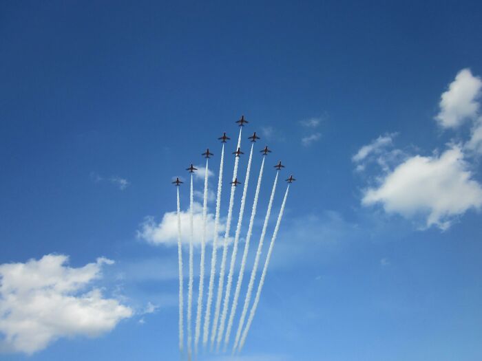 Formation of jets flying in the blue sky, leaving trails behind them.