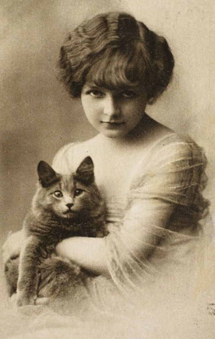 A young girl from decades past holding a cat, reflecting how much the world has changed over the years.