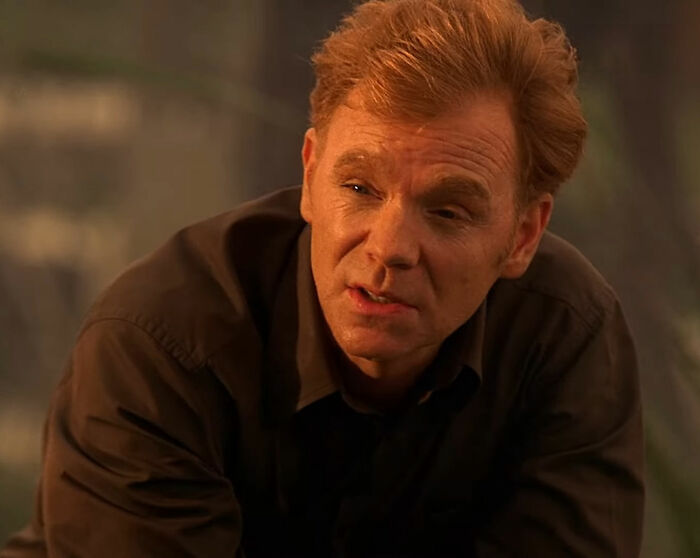 Actor in a scene, wearing a dark shirt, portraying a thoughtful expression.