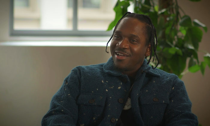 Smiling celebrity in a cozy room with plants, wearing a blue jacket, discussing a petty moment.
