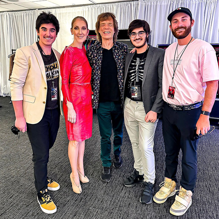 Céline Dion poses with several men, including bearded twin sons, all smiling in a casual setting. Céline Dion poses with several men, including bearded twin sons, all smiling in a casual setting.
