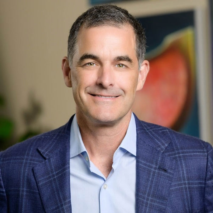 A man in a blue suit smiling indoors, related to Boston Celtics investor group led by private equity mogul. A man in a blue suit smiling indoors, related to Boston Celtics investor group led by private equity mogul.