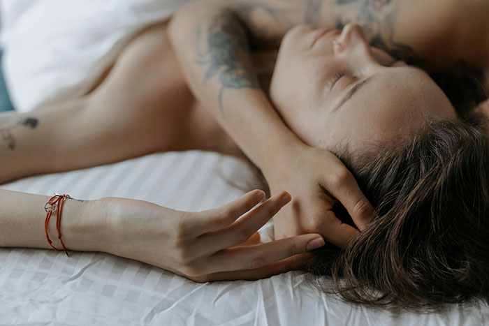 Person resting on bed with tattoos visible, representing a scene related to uncovering a cheating affair.